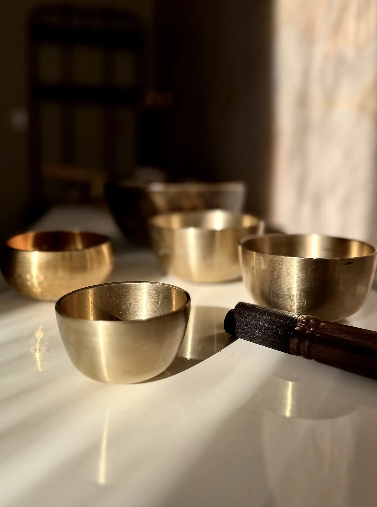 Singing bowls and a mallet on a light surface, Résonance studio, Paris 16