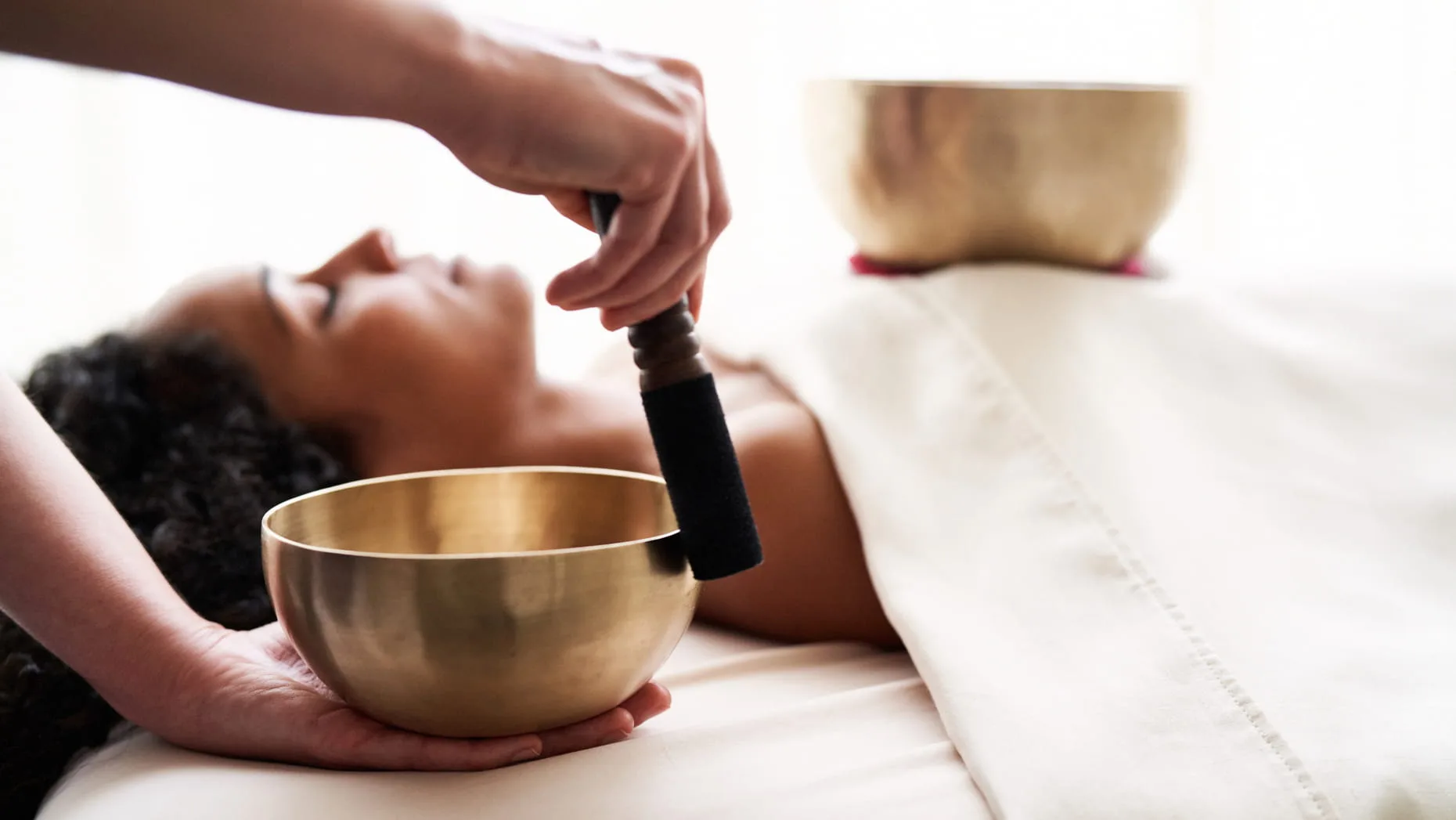 Singing bowl resting near the face of someone lying down during a one-to-one session