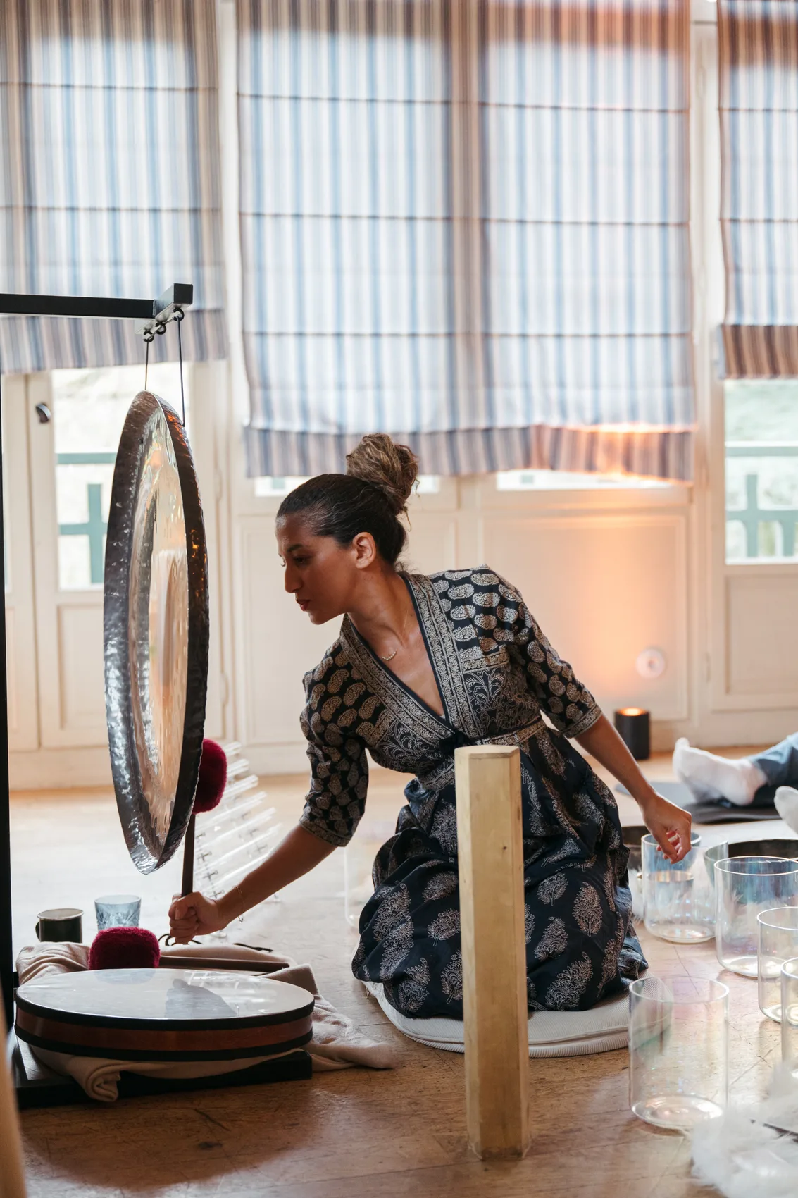 Practitioner holding a frame drum above a participant during a session